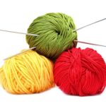 Three balls of wool with knitting needles isolated on white back